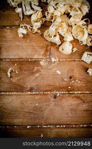 Wooden shavings on the table. On a wooden background. High quality photo. Wooden shavings on the table. On a wooden background.