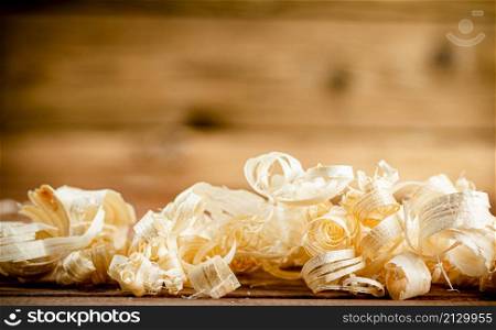 Wooden shavings on the table. On a wooden background. High quality photo. Wooden shavings on the table.