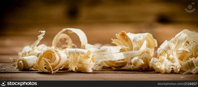 Wooden shavings on the table. On a wooden background. High quality photo. Wooden shavings on the table.