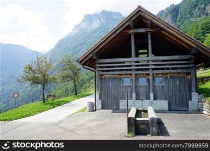 Wooden shed and fountain near road in Switzerland