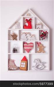 Wooden shelves in shape of cozy home with Christmas decorations. Christmas decorations on the wall