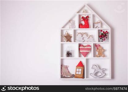 Wooden shelves in shape of cozy home with Christmas decorations. Christmas decorations on the wall