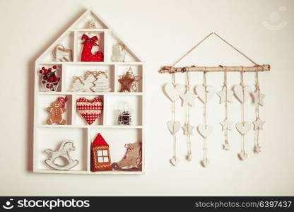 Wooden shelves in shape of cozy home with Christmas decorations. Christmas decorations on the wall