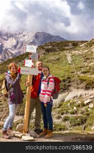 wooden sign on a trekking path and family at the Dolomites mountains at the Italy. Tre Cime di Lavaredo