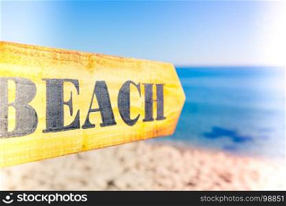 Wooden sign pointing to a beach on a sunny day