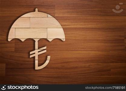 Wooden silhouette of Turkish Lira sign under umbrella