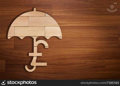 Wooden silhouette of UK pound currency under umbrella