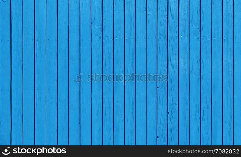 Wooden slat fence with parallel planks with blue paint.. Wooden fence with parallel planks with blue paint.