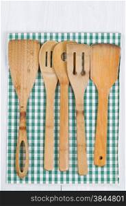 Wooden spatula, spoons with striped cloth napkin on white wood. Format in vertical layout.