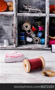 Wooden spool of red thread on the background of sewing tools.Selective focus. Sewing kit and accessories
