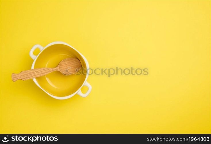 wooden spoon and empty yellow soup plate on white table, top view, copy space