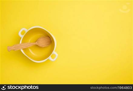wooden spoon and empty yellow soup plate on white table, top view, copy space