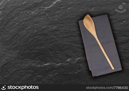 Wooden spoon and kitchen towel on slate.. Wooden spoon and kitchen towel on slate