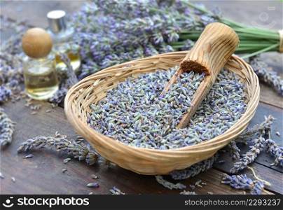 wooden spoon in a little basket  full of petals of lavender flowers  and oil essential bottles background