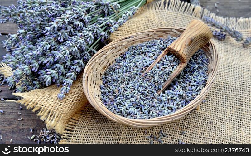 wooden spoon in a little basket full of petals of lavender flowers on a wooden table