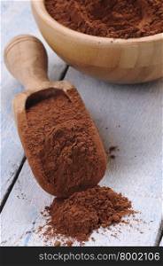 Wooden spoon of cocoa on table