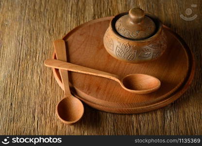 Wooden spoon, plate, clay pot on old table. Copy space