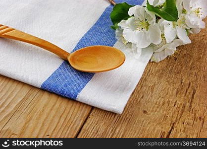 wooden spoon with a flowers and dishcloth on old wooden table