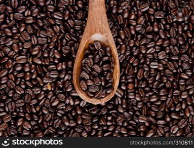 Wooden spoon with coffee beans on beans background texture