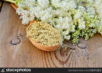 Wooden spoon with dried flowers of meadowsweet, a bouquet of fresh flowers of meadowsweet against a wooden board