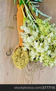 Wooden spoon with dried flowers of meadowsweet, a bouquet of fresh flowers of meadowsweet on a wooden boards background