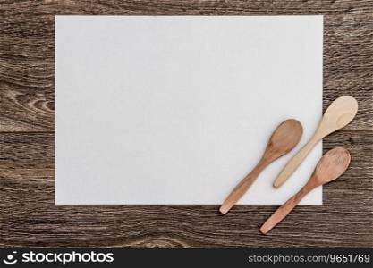 Wooden spoons on white paper and brown wooden background with copy space