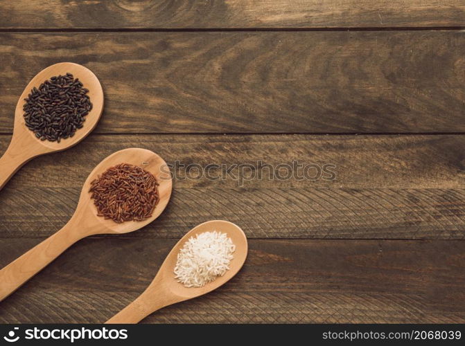 wooden spoons with three different type rice grains wooden plank