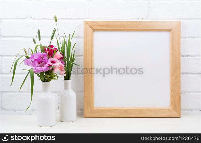 Wooden square picture frame mockup with pink and red godetia clarkia flowers. Empty frame mock up for presentation design. Template framing for modern art.