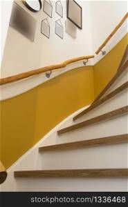 wooden stair with yellow wall and blank frames hanging, retro modern design interior. wooden stair with yellow wall and blank frames hanging, retro modern design