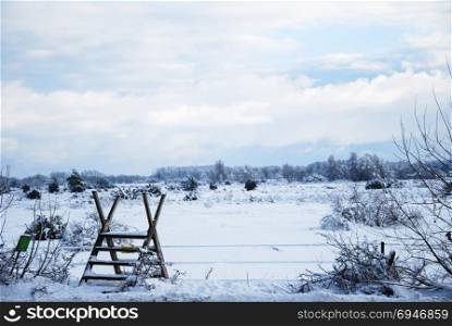 Wooden stile in a wintry landscape at the swedish island Oland