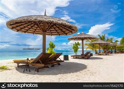 Wooden sunbed and umbrella on tropical beach in the Maldives at summer day