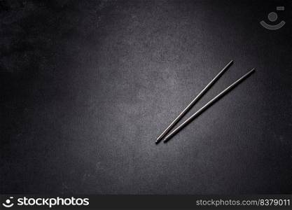 Wooden sushi sticks on a dark concrete background. Japanese Asian cuisine. Wooden sushi sticks on a dark concrete background