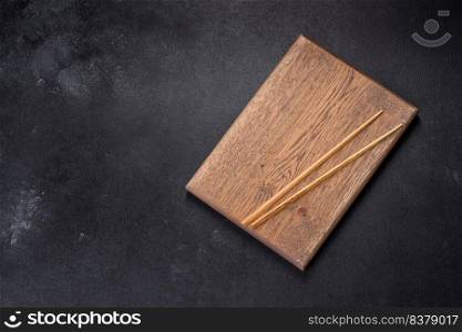 Wooden sushi sticks on a dark concrete background. Japanese Asian cuisine. Wooden sushi sticks on a dark concrete background