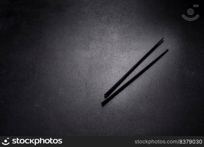 Wooden sushi sticks on a dark concrete background. Japanese Asian cuisine. Wooden sushi sticks on a dark concrete background