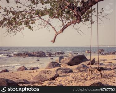 Wooden swing hanging on big tree at Khao Lak beach in Phang nga province, Thailand. Vintage style color.