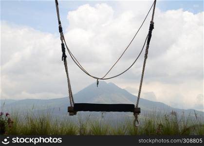 Wooden swing on the rope with view of Batur volcano as background