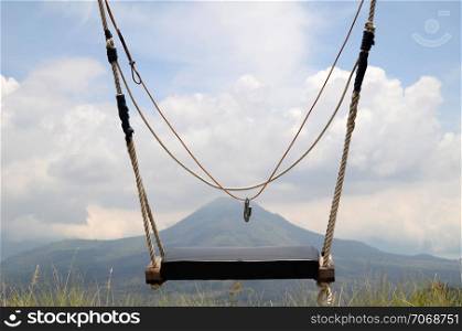 Wooden swing on the rope with view of Batur volcano as background