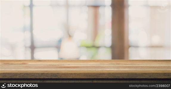 Wooden tab≤top with blurred peop≤in coffee shop and cafe background for display monta≥,©space.