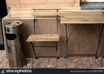 Wooden table and chair outside cafe with litter bin near. Wooden table and chair outside cafe with litter bin