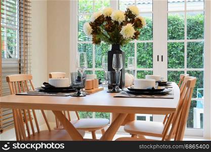 wooden table and chairs in dining room with elegant table setting