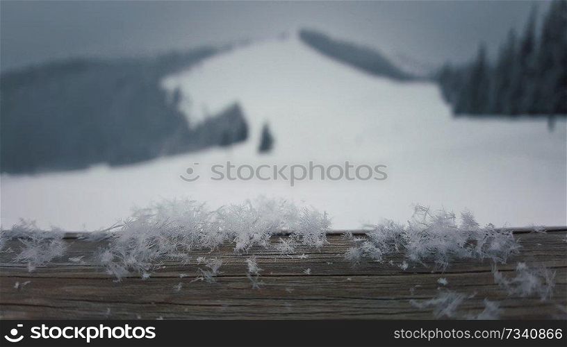 Wooden table covered with soft snowflakes on a beutiful mountains background