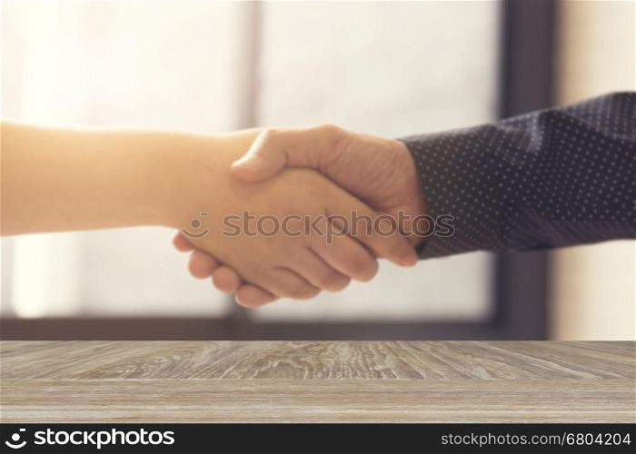 wooden table for display or montage your product with blur background of businessman handshaking for business acquisiton concept