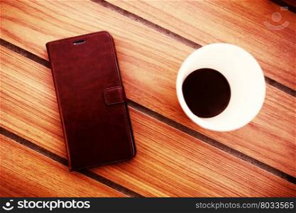 Wooden table in cafe with cell phone and coffee background