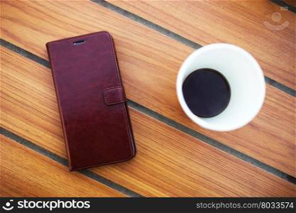 Wooden table in cafe with cell phone and coffee background