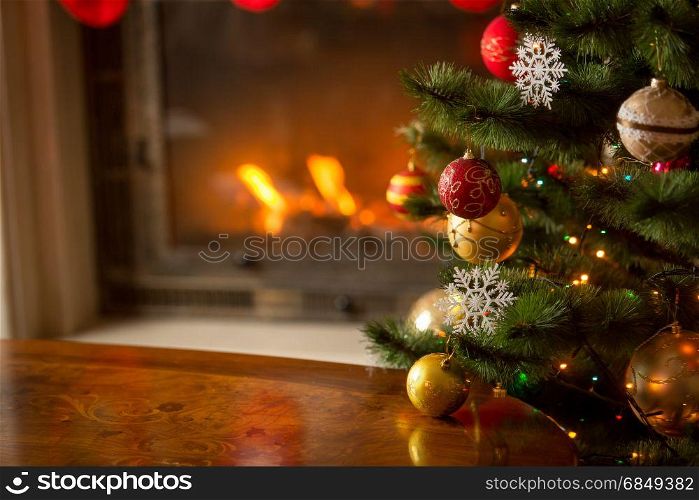 Wooden table in front of decorated fireplace and Christmas tree. Place for text. Suitable for Christmas background.