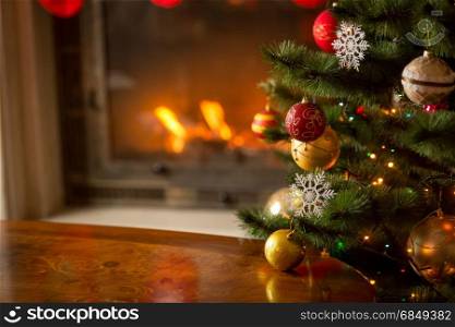 Wooden table in front of decorated fireplace and Christmas tree. Place for text. Suitable for Christmas background.