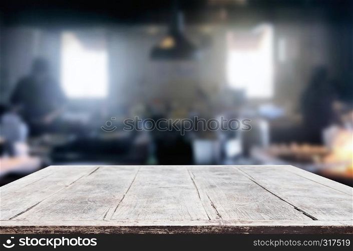 Wooden table on abstract blurred kitchen with Chef cooking in restaurant background and space for decoration display or montage your products.