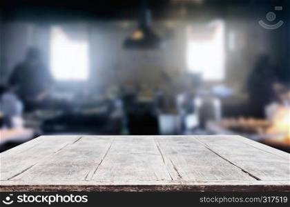 Wooden table on abstract blurred kitchen with Chef cooking in restaurant background and space for decoration display or montage your products.