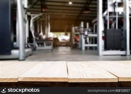 Wooden table on blurred background of fitness gym interior of modern club with equipment for your photomontage or product display
