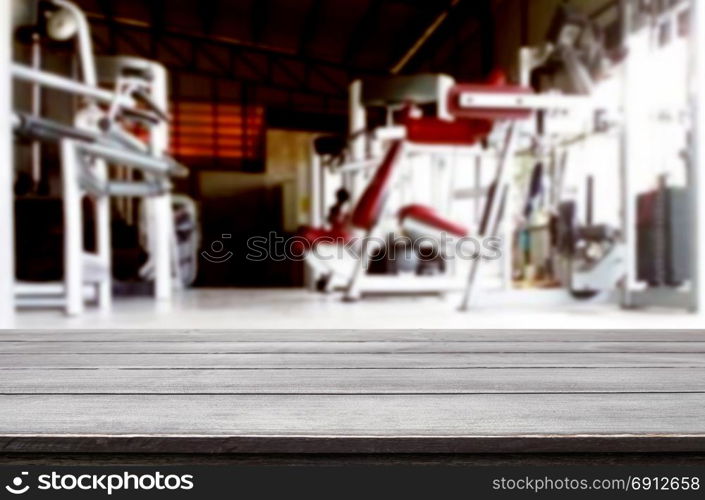 Wooden table on blurred background of fitness gym interior of modern club with equipment for your photomontage or product display